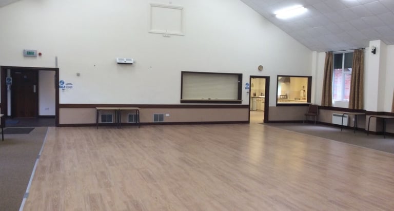a large village hall room with a wooden floor