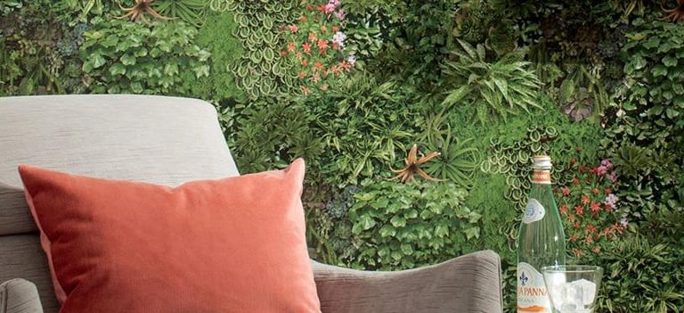 Modern living room featuring a vertical garden wall behind a grey armchair with an orange cushion.