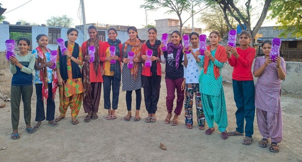12 girls holding up washable sanitary napkins.