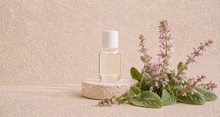 Salvia sclarea flowers and leaves beside pale yellow clary sage essential oil