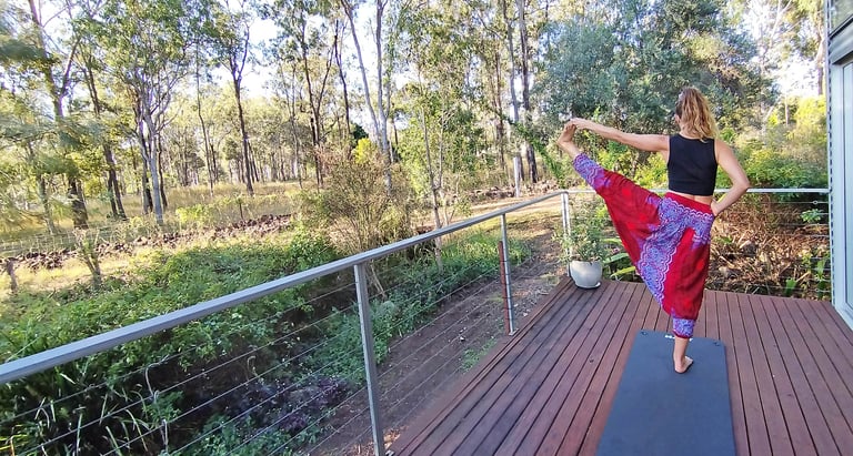 woman doing yoga on a deck with natural bush background