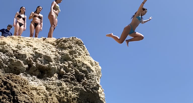 a woman jumping into the water from a cliff