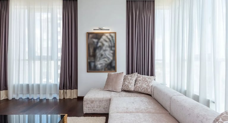Elegant open concept living and dining room featuring white furniture, soft cream curtains, and a te