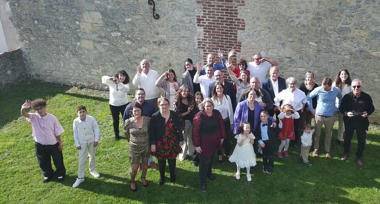 grand groupe de famille et d'amis souriants posant pour une photo sur une pelouse verte devant un mu