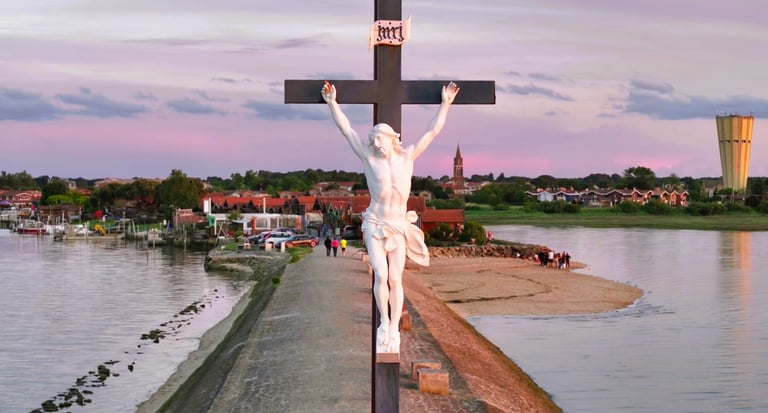 Statue de crucifix blanc surplombant un village côtier et l'eau au coucher du soleil.