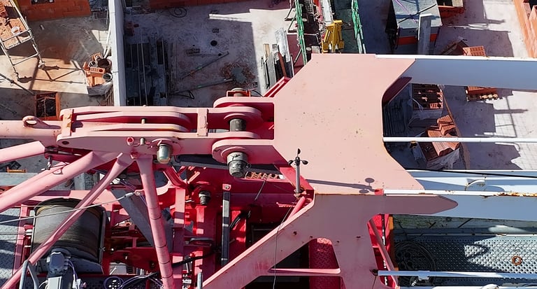 Vue aérienne d'un assemblage de grues à tour industrielle rouge sur un chantier résidentiel.