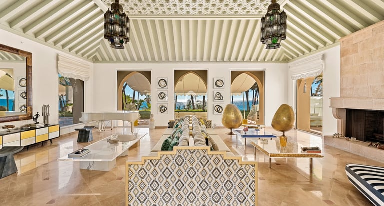 Elegant living room with grand piano, fireplace and arched ocean views