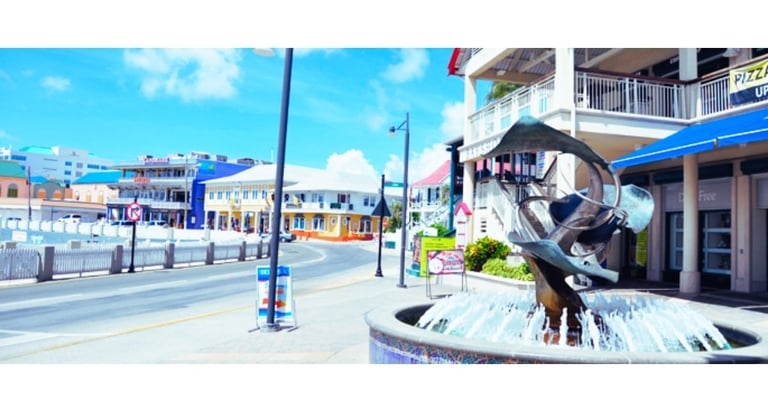 Rua de lojas e galerias em George Town, Ilhas Cayman, com fachadas coloridas e movimento de turistas.