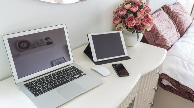 TechAid spec laptop computer sitting on a desk with a vase of flowers
