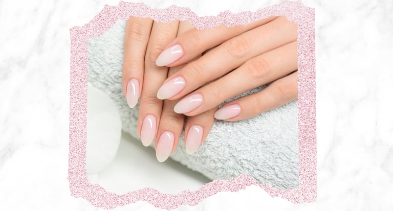 Elegant nude ombre almond shaped nails over a soft spa towel with a marble background.