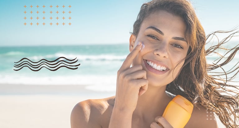 Smiling woman applying sunscreen to her face at the beach, promoting sun protection and skincare.