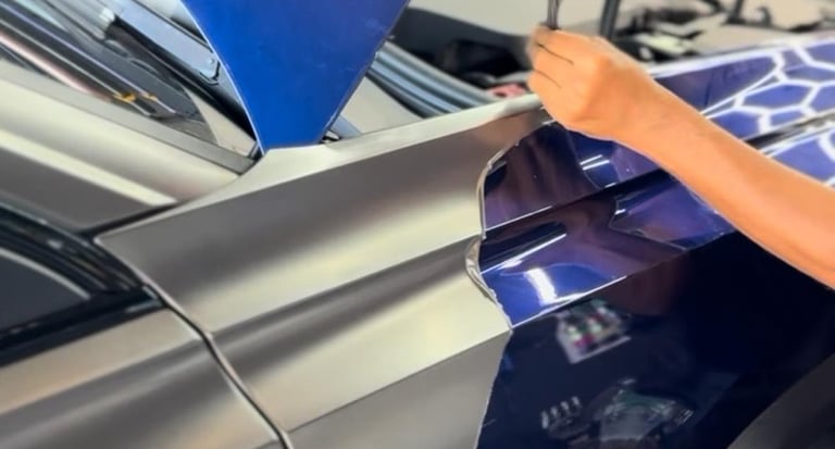 Technician peeling protective film from navy blue vinyl wrap