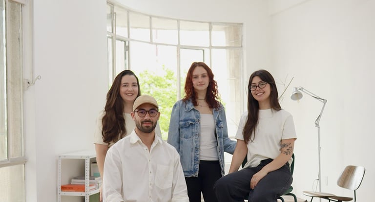 Diverse creative team posing together in a bright, modern office with parquet flooring.