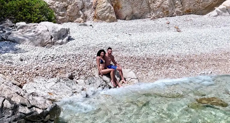 Drone view of a couple on the secluded beach under cliffs at Ciovo Island, seen on a private boat tour from Split, Croatia.
