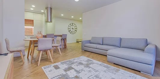 Modern open plan living room with a grey sectional sofa, dining set, and hardwood floors.