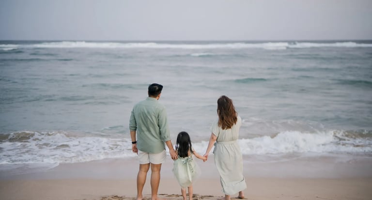 Family standing together facing the ocean during a beach family photography session in Bali.