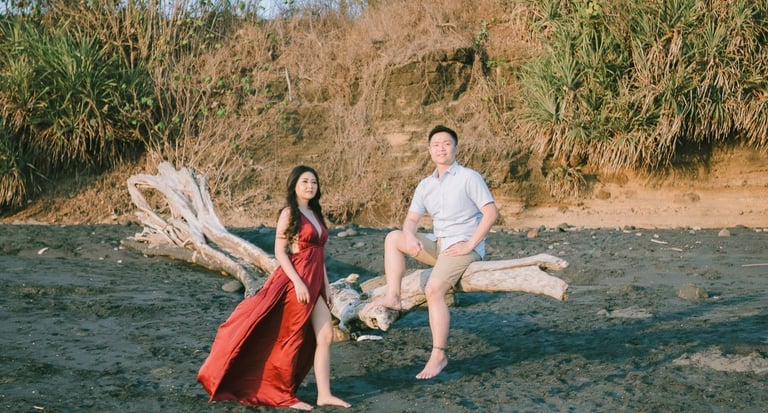 Wide beach portrait of intimate couple near rock formation at Pantai Nyanyi Bali.