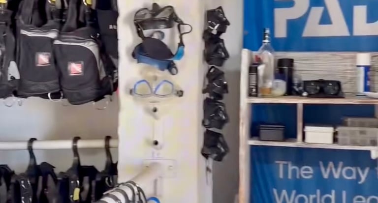 Scuba diving rental shop featuring PADI signs, snorkeling masks, and BCD jackets on racks.