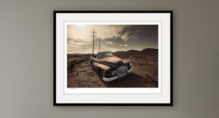 Old rusted classic car with telephone poles and mountains in the background
