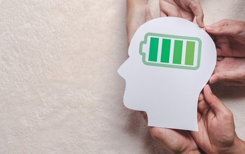 a person holding a paper cutout of a head with a battery