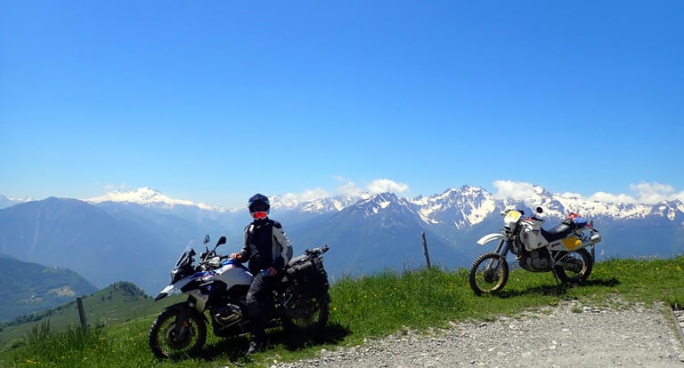 two people on a mountain top with mountains in the background