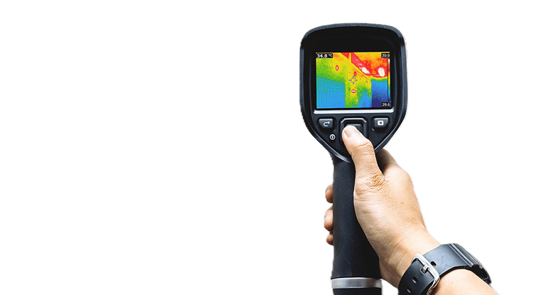 Hand holding an infrared thermal imaging camera displaying a heat map of a building interior.