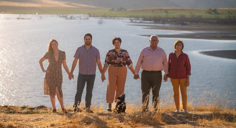 Family portrait photographer in Visalia capturing a group by a lake at sunset.