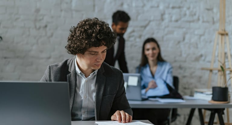 Professional businessman reviewing documents at a laptop in a modern industrial office space.