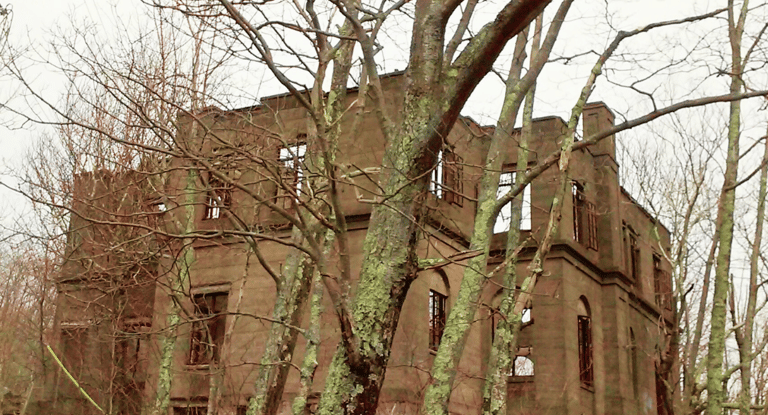 Crumbled concrete ruins of an abandoned hotel hidden deep in a foggy forest near Woodstock, New York, with vines and moss gro