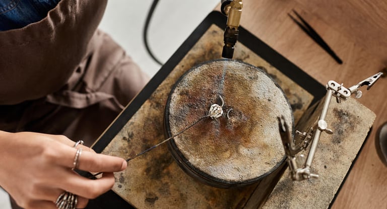 Artesana joyera utilizando un soplete para soldar una pieza de plata en un taller profesional