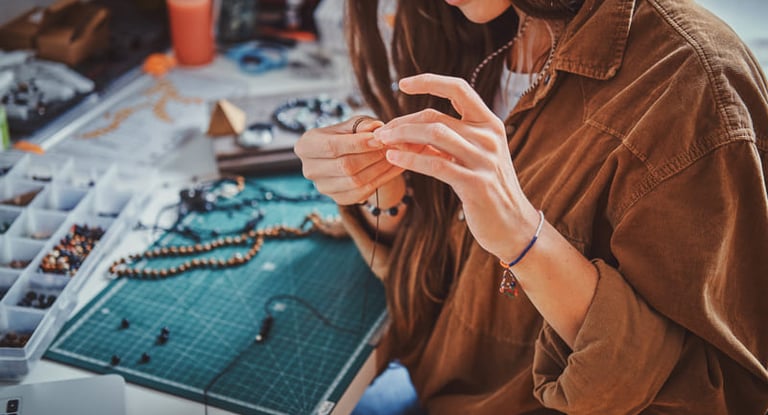 Artesana creando un collar artesanal de cuentas, trabajando a mano en su mesa de trabajo