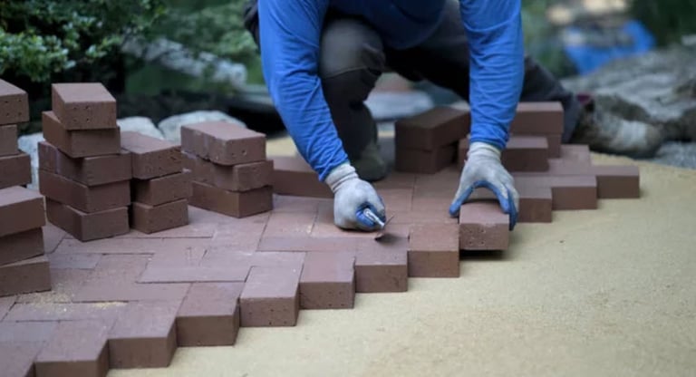 a person laying red brick in a herringbone pattern