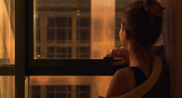 woman looking out a window in the evening, reflecting on relationship challenges