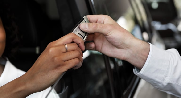 auto1Locksmith standing outside the car giving Man setting in a car his new key