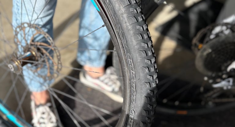 A person repairing a mountain bike tire and rim with knobby tread for off-road cycling.