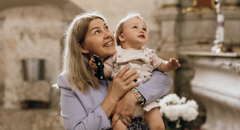 Krikštynų fotografija - močiutė ant rankų laiko savo anūką