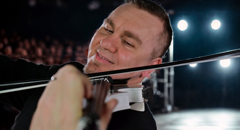 Professional male violinist playing a white electric violin during a live stage performance.