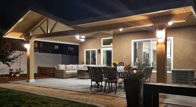 Alumawood patio cover with lighting and patio furniture taken at night.ht