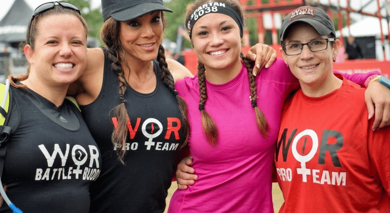 Smiling female athletes from the WOR Pro Team posing together at a Spartan obstacle course race.