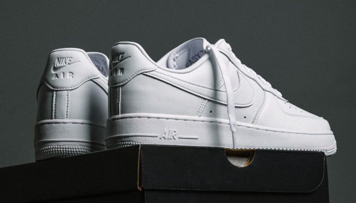 Zapatillas Nike Air Force 1 blancas de cuero de caña baja sobre cajas de zapatos negras.