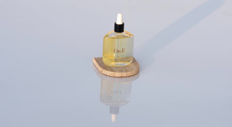 Golden facial oil serum bottle with dropper on a stone pedestal with reflective background.