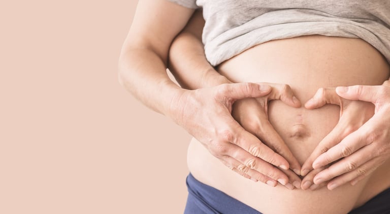 a pregnant woman holding her hands in the shape of a heart