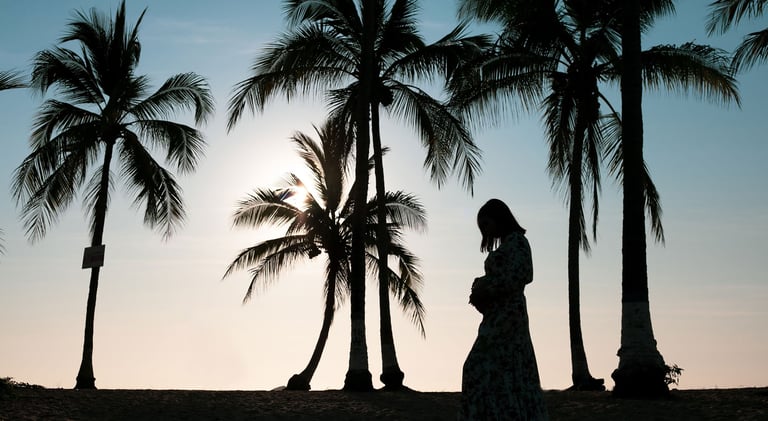 una mujer embarazada en la playa entre palmeras en el atardecer