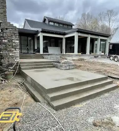 a house with a large concrete patio with steps leading up to a large house