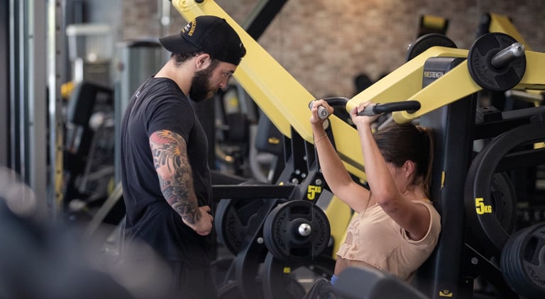 moi en train de coacher ma cliente emmie sur une shoulder press tecnogym