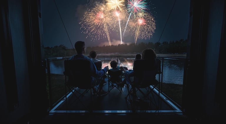 a family watching fireworks in the night sky on an RV deck