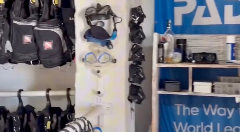 Scuba diving rental shop featuring PADI signs, snorkeling masks, and BCD jackets on racks.