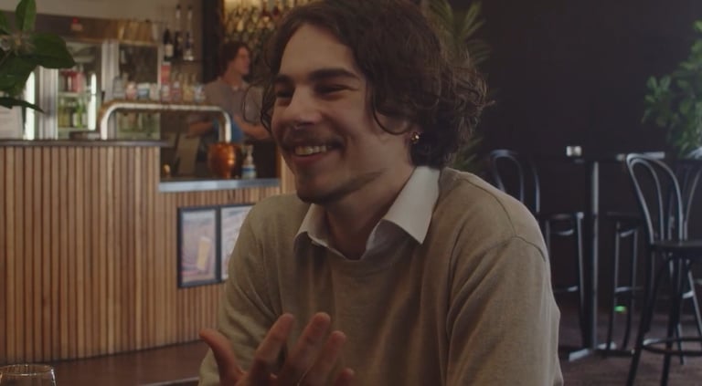 a man sitting at a table with a glass of wine