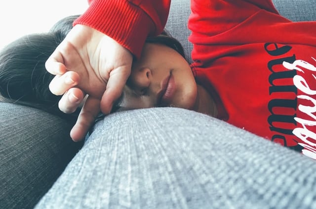 a woman is laying on a couch with her hands on her head