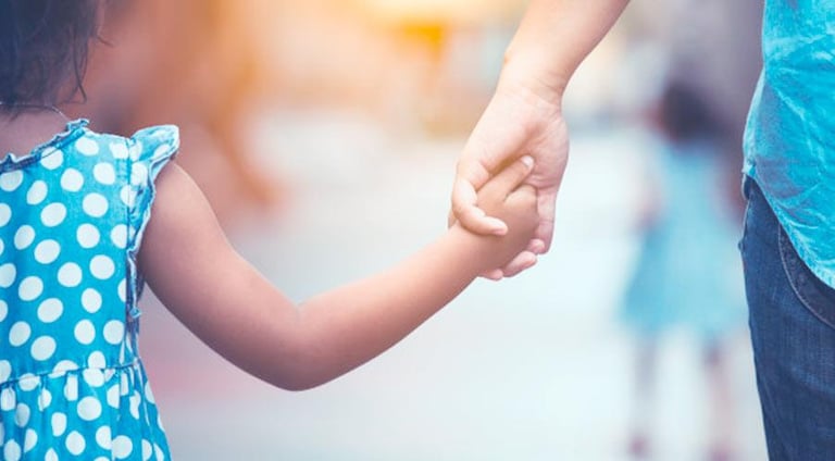 a young girl holding hands with her father